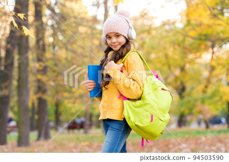 modern education. child with backpack and book in forest. knowledge day. kid fall clothes fashion. So beautiful. happy kid walk in autumn park. small girl wear headphones. back to school 94503590