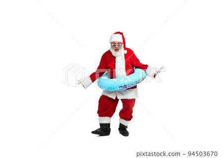 Portrait of senior man in image of Santa Claus posing with swimming circle and sunglasses isolated over white background. 94503670