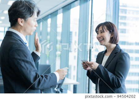 Middle man and young woman exchanging business cards 94504202