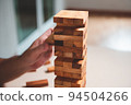 Wooden blocks toy puzzle with human hand on table at home background. Entertainment and business concept. 94504266