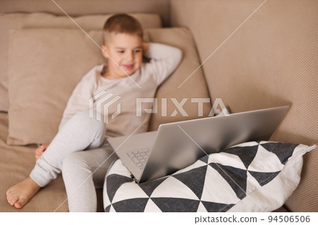 Child at home watching cartoon on the computer. Little boy and a laptop. Modern kid and education technology. Child at home watching cartoon on the computer. Little boy and a laptop. Modern kid and education technology. 94506506