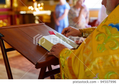 a priest with a prayer book in the church during the church worship. 94507996