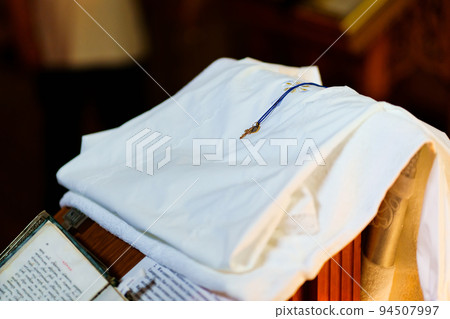 a white baptismal shirt and a cross on a table in the church during baptism. 94507997