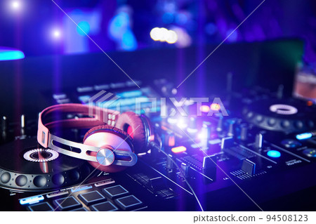 Pink DJ headphones on sound mixer and turntables in night club 94508123