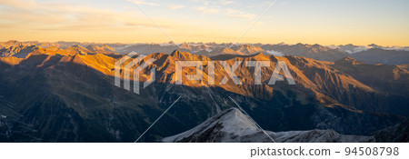 Alpine mountain peaks illuminated by rising sun Alpine mountain peaks illuminated by rising sun 94508798