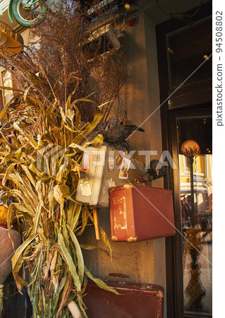 Cafe entrance decorated in Halloween style, with beautiful pumpkins, dried flowers, crows and antiques Cafe entrance decorated in Halloween style, with beautiful pumpkins, dried flowers, crows and antiques 94508802