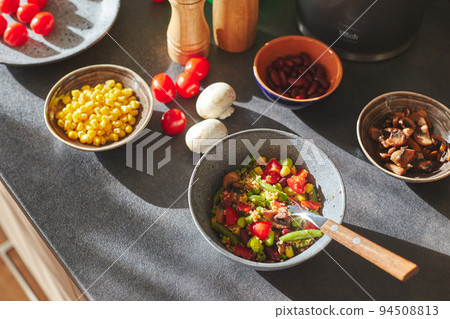 Sunliht modern kitchen with plate of quinoa filled with vegetables and ingredients on the countertop. Sunliht modern kitchen with plate of quinoa filled with vegetables and ingredients on the countertop. 94508813