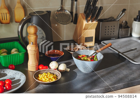 Sunliht modern kitchen with plate of quinoa filled with vegetables and ingredients on the countertop. Sunliht modern kitchen with plate of quinoa filled with vegetables and ingredients on the countertop. 94508814
