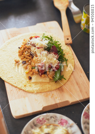 Cooking burrito, Mexican food at home. Grilled wheat tortilla stuffed with cheese, chicken, beans, corn, lettuce, tomato and sauce Cooking burrito, Mexican food at home. Grilled wheat tortilla stuffed with cheese, chicken, beans, corn, lettuce, tomato and sauce 94508815