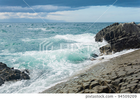 rocky seashore formed by columnar basalt against the surf, coastal landscape of the Kuril Islands 94509209