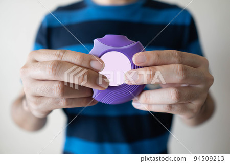 Young man using medicine dry powder inhaler for treatment asthma or COPD diseases. Pharmaceutical product is used to treat lung inflammation and prevent asthma attack. Close up. 94509213