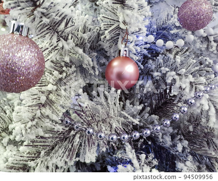 Purple shiny balls on the Christmas tree. White pearl beads on spruce branches. The branches are covered with frost. Christmas or New Year background 94509956