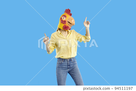 Young girl wearing funny yellow chicken mask dancing isolated on blue background 94511197