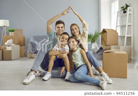 Happy family with kids sitting under symbolic roof in their new house on moving day 94511256
