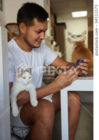 Young man in t shirt holding a cat. 94511573