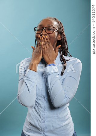 Exhausted african american person catching a yawn while putting hand over mouth. Tired sleepy young adult woman yawning mouth wide open because of fatigue from overtime work 94511574