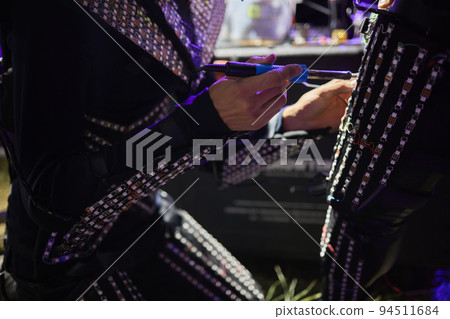 dancers in led suits on dark background, wire repair. 94511684