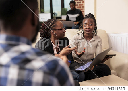 Company employees working on startup report, using documents and research data on laptop to create corporate presentation. People doing teamwork collaboration in business office. 94511815