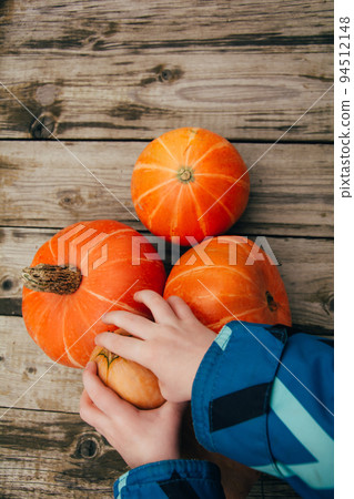 Child's hands take small pumpkins. Halloween and Thanksgiving season. Harvesting, colors of autumn 94512148