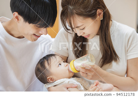 A couple giving milk to their baby 94512178