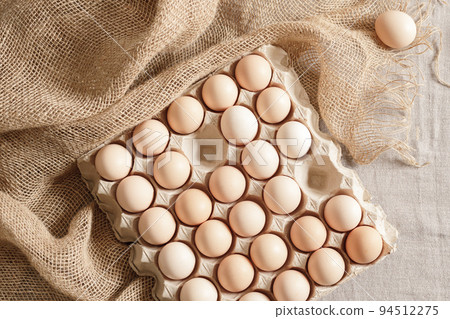 Fresh organic chicken eggs in carton pack or egg paper container on a sacking. Zero waste packaging concept Fresh organic chicken eggs in carton pack or egg paper container on a sacking. Zero waste packaging concept 94512275
