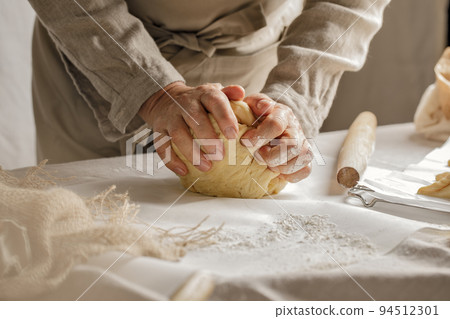 Womens hands, flour and dough. A woman is preparing a dough for home baking. Concept of home cooking with organic and natural ingredients. Zero waste concept Womens hands, flour and dough. A woman is preparing a dough for home baking. Concept of home cooking with organic and natural ingredients. Zero waste concept 94512301