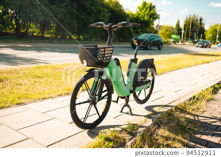 Modern green electric bike battery on a cycle in the street for rent 94512911