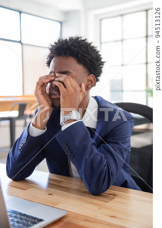 Portrait of unhappy male office worker rubbing eyes Portrait of unhappy male office worker rubbing eyes 94513126