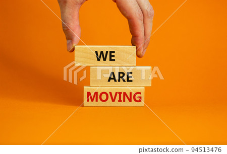 We are moving symbol. Wooden blocks with words 'We are moving'. Beautiful orange background, businessman hand. Business, we are moving concept, copy space. 94513476