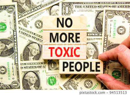 No more toxic people symbol. Concept words No more toxic people on wooden blocks on a beautiful background from dollar bills. Psychologist hand. Business, psychological no more toxic people concept. 94513513