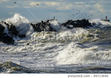 Big waves crash against the harbor breakwater concrete tetrapods during stormy weather 94513698