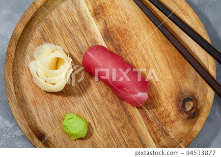 View from above of pieces of tuna on wooden board and ginger with wasabi to be cut and prepare sushi. View from above of pieces of tuna on wooden board and ginger with wasabi to be cut and prepare sushi. 94513877