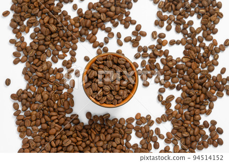Fragrant roasted coffee beans on a white background and a small cup. Fragrant roasted coffee beans on a white background and a small cup. 94514152