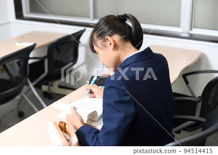 Back view of a female student studying during class 94514415
