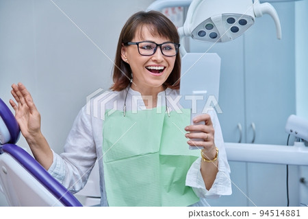Middle-aged female in dental office looking in mirror 94514881