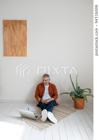 A bearded man in terracotta shirt working on the project and looking involved A bearded man in terracotta shirt working on the project and looking involved 94516006
