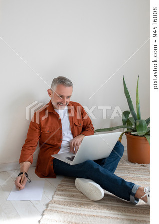 A bearded man in terracotta shirt working on the project and looking involved A bearded man in terracotta shirt working on the project and looking involved 94516008