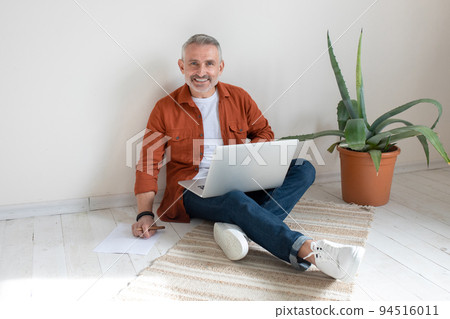 Bearded man in terracotta shirt working from home 94516011