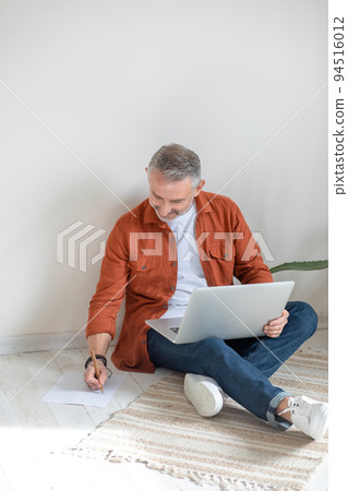 Bearded man in terracotta shirt working from home Bearded man in terracotta shirt working from home 94516012