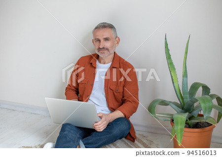 Bearded man in terracotta shirt working from home Bearded man in terracotta shirt working from home 94516013