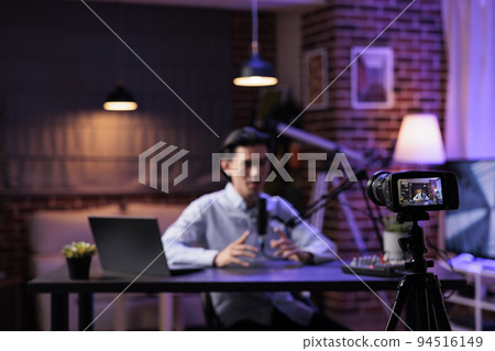Content creator broadcasting talk show on camera, recording podcast episode with audio equipment. Filming video for internet channel, livestreaming social media vlog at sound station with laptop. 94516149