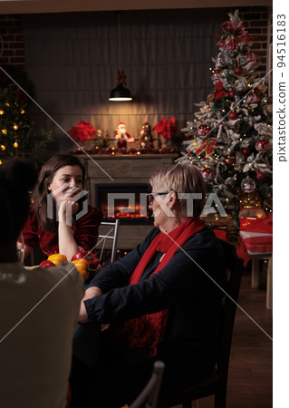 Daughter talking with mom at christmas festive dinner, family having conversation. Xmas celebration in beautiful decorated place with warm evening candle light, fir tree, garlands on background 94516183