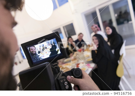 Professional videograph recording video while Muslim family having iftar together during Ramadan 94516756