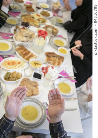 Muslim family making iftar dua to break fasting during Ramadan. 94516799