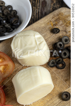 Fresh cow's milk cheese is cut on a board 94516852