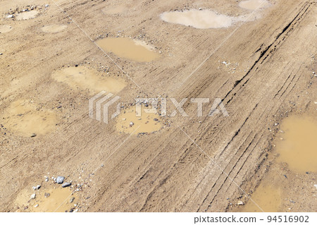 a dirt road with a lot of water holes a dirt road with a lot of water holes 94516902