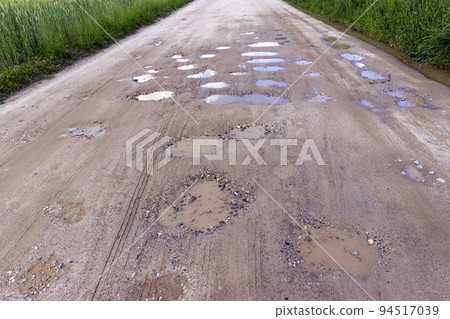 a dirt road with a lot of water holes a dirt road with a lot of water holes 94517039