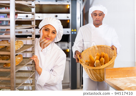 Woman transporting a cart with bread in bakery Woman transporting a cart with bread in bakery 94517410