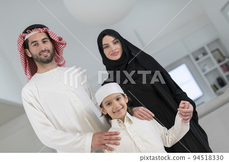 Portrait of a young happy Arabian Muslim family couple with a son in traditional clothes spending time together 94518330