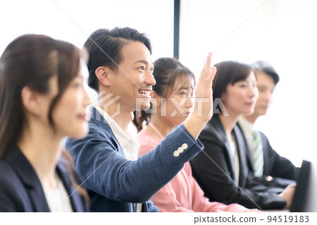 Business person sitting at the desk and raising his hand seminar training meeting business image Business person sitting at the desk and raising his hand seminar training meeting business image 94519183